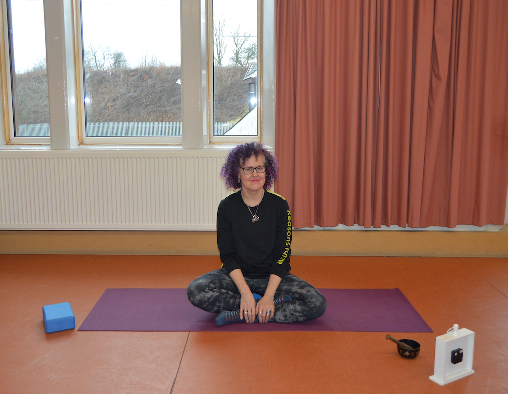 Caron Jones yoga teacher sitting on yoga mat and smiling