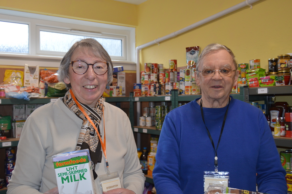 Woman and man working at foodbank holding groceries